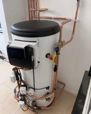 Unvented hot water cylinder with neatly run copper pipework and controls.
