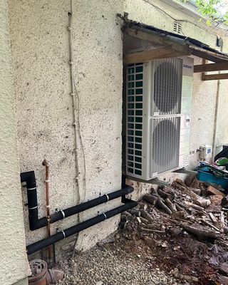 Samsung air source heat pump mounted on wall brackets with insulated pipe runs.