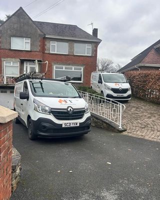 Two IT Plumbing and Heating branded vans parked on a customer driveway.